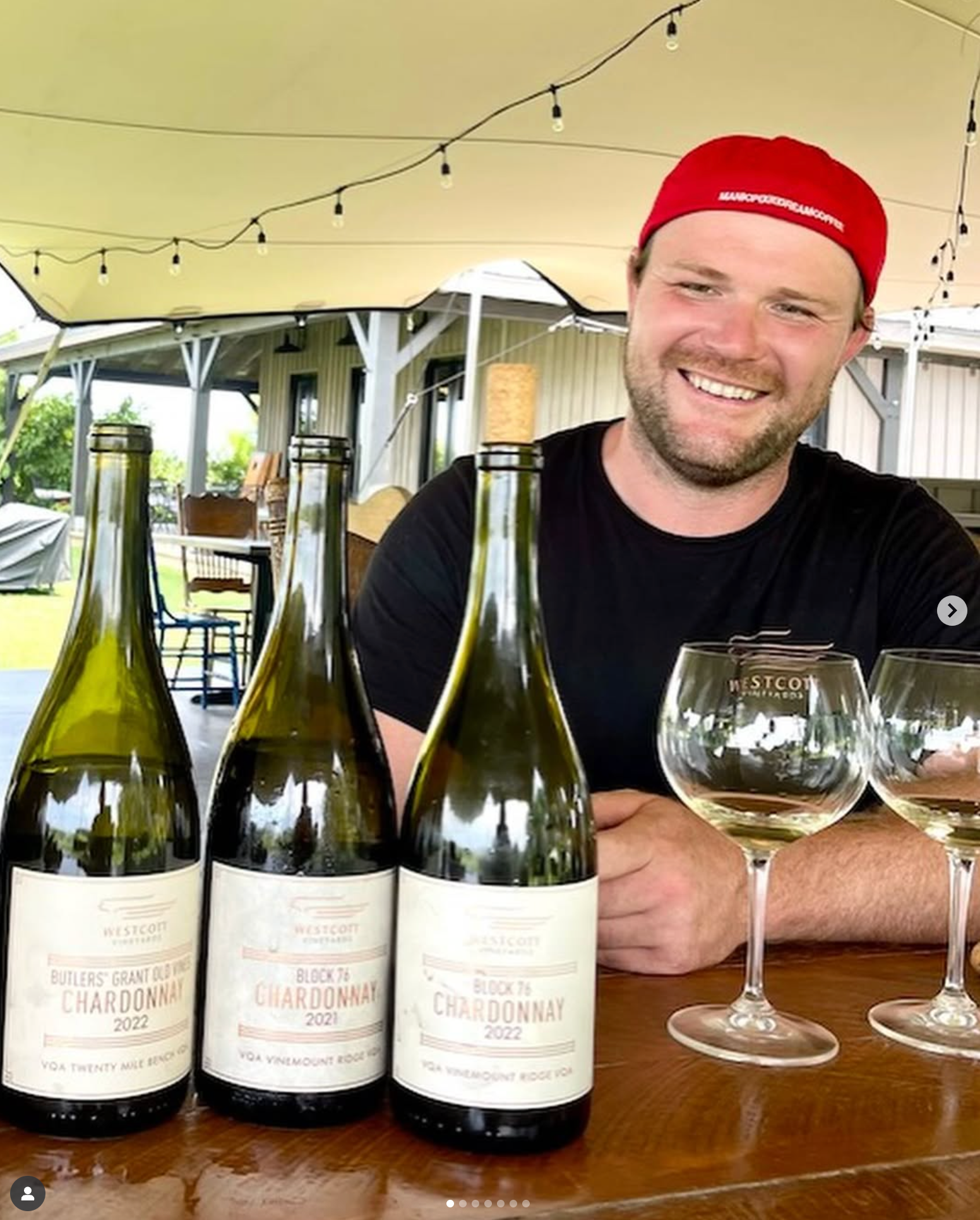 Winemaker Casey Kulczyk sits under the tent on the patio in front of three bottles of Westcott Vineyards' Chardonnay.