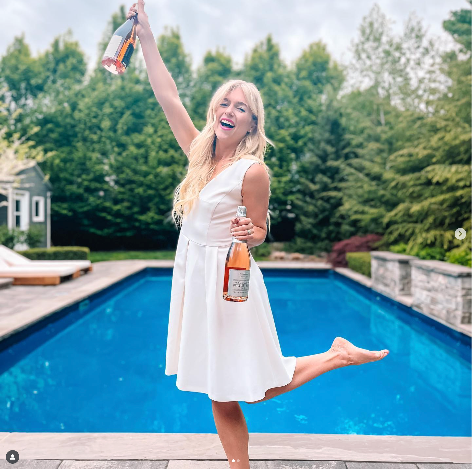 Westcott Vineyards' superfan Alii Arruda poses in front of her backyard pool with two bottles of Westcott Vineyards' Pinot Noir Rosé.
