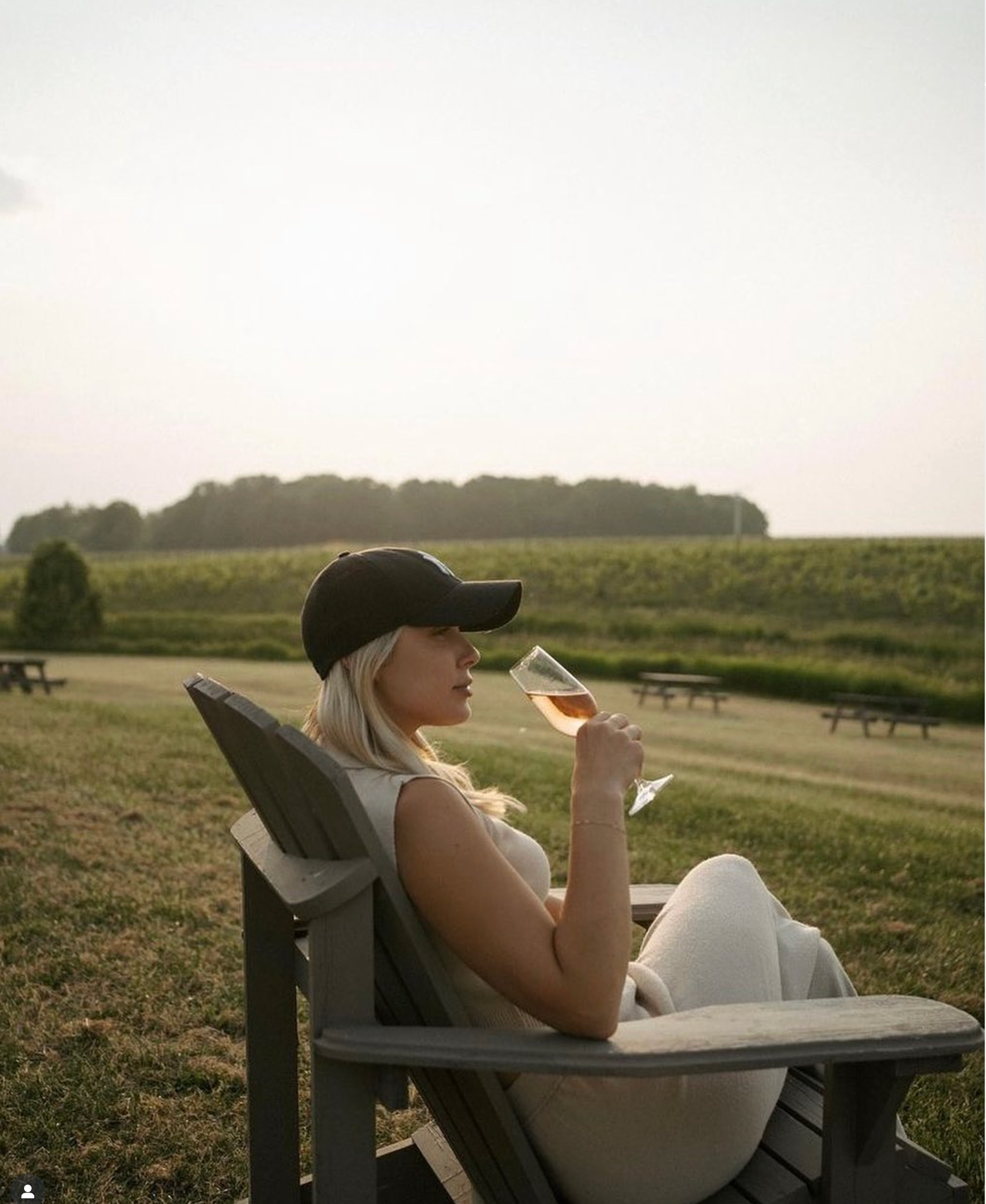 A wine club member sits in an Adirondack chair, sipping a glass of Westcott Vineyards' exclusive pinot noir rosé sparkling. 