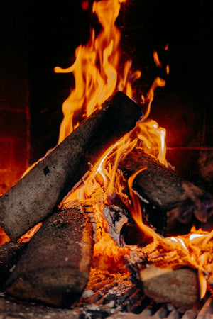 Firewood burning in a fireplace with flames and embers.
